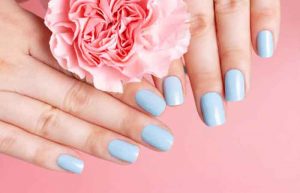 Female hands with manicure on flower on a pink background, top view