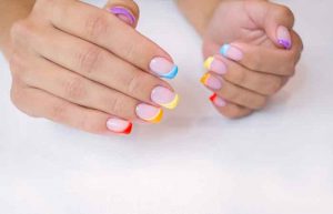 Hands of a young woman with a manicure. The nails are covered with gel polish with colored French.