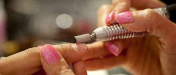 shot of manicurist using a machine to file a customer hand