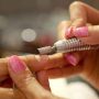 shot of manicurist using a machine to file a customer hand