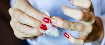 Young woman with long red nails removing nail polish